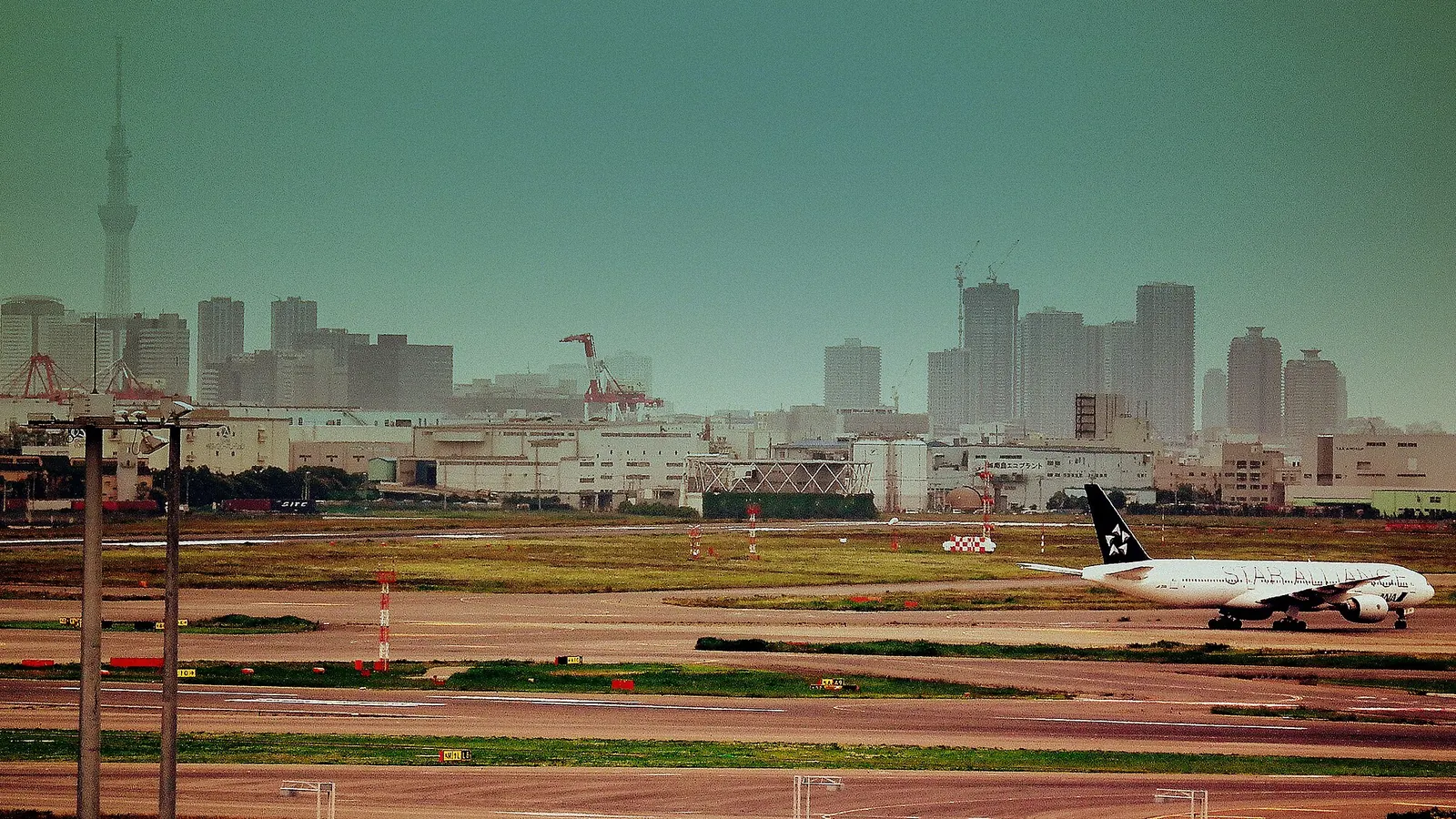 羽田空港の誘導路を走行するスターアライアンス塗装の旅客機。背景に東京の街並み