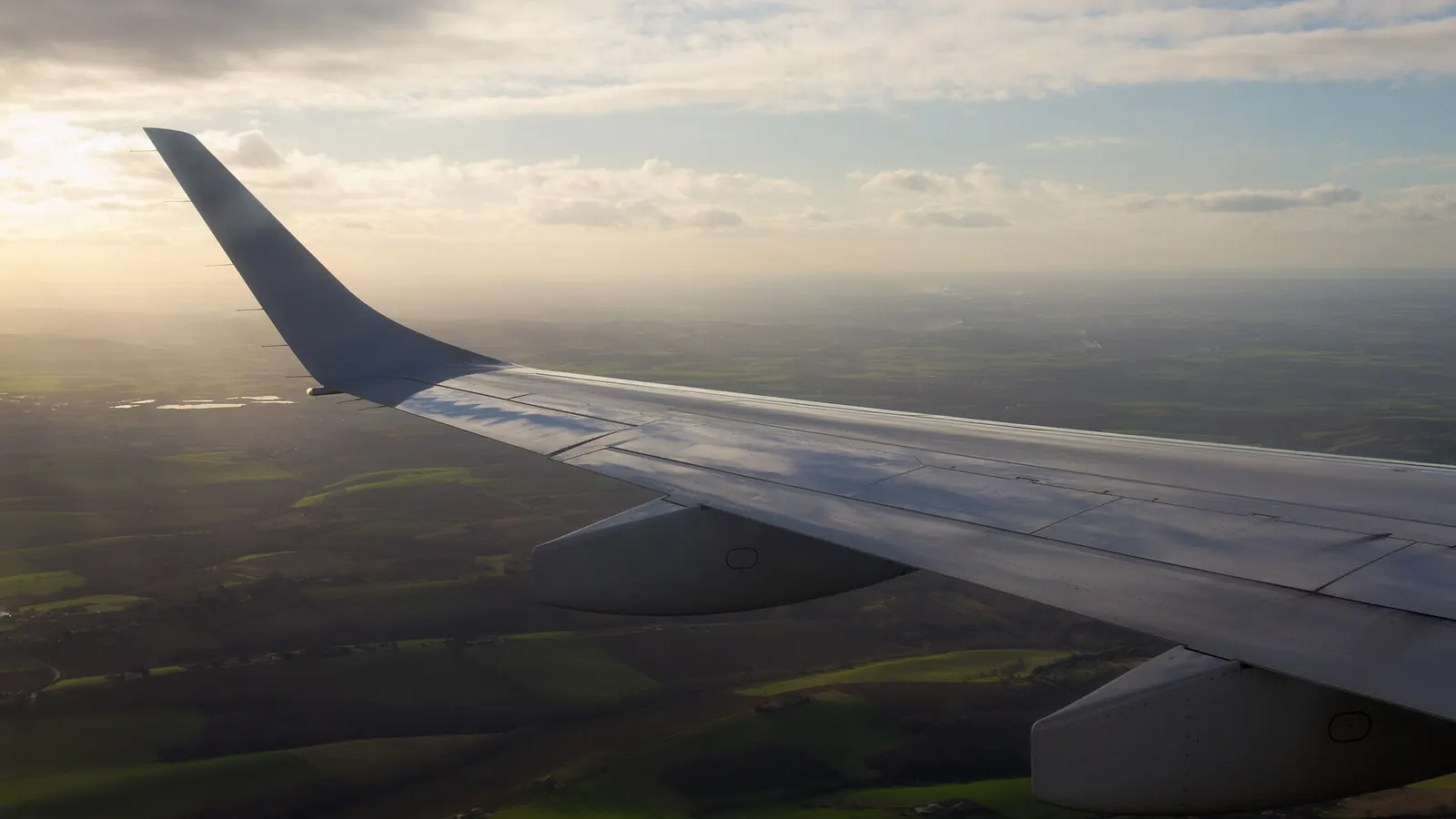 夕暮れの空を飛ぶ旅客機の翼を機内の窓から見た風景
