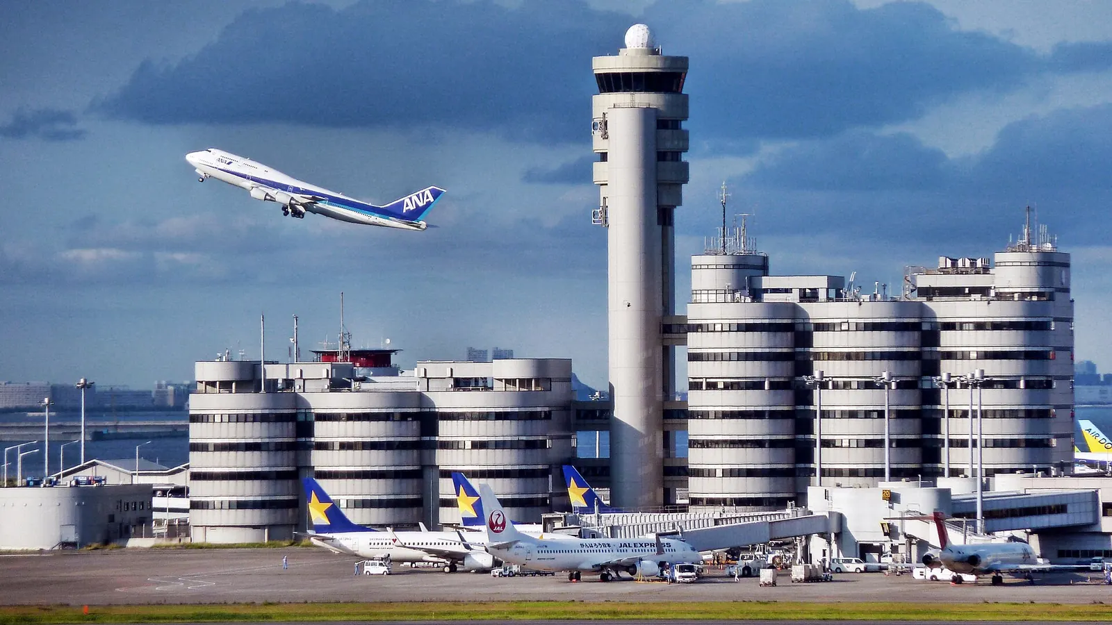 羽田空港の管制塔と第 1 ターミナル。駐機する旅客機と離陸する機体