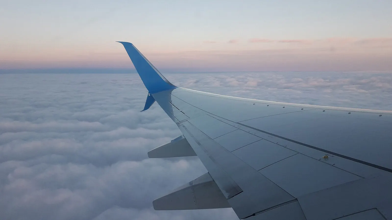 雲海の上を飛ぶ旅客機の翼。海上や山岳地帯では地上アンテナ方式の電波が届きにくい